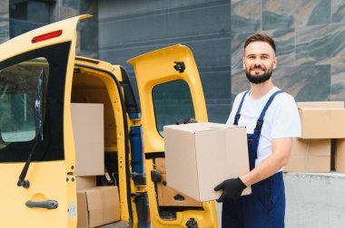 Kurye, açık bir teslimat minibüsünden bir paket taşıyor. Verimli nakliye ve lojistik hizmetleri sunuyor.