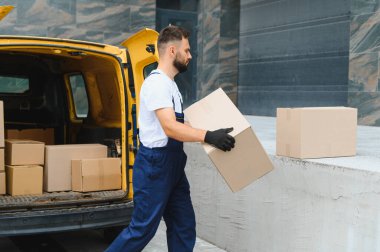 Kurye, açık bir teslimat minibüsünden karton bir kutu taşıyordu. Kalabalık şehir sokaklarında etkili bir şekilde paket taşıyordu.