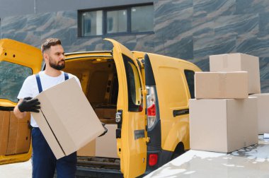 Kurye, açık bir teslimat minibüsünden karton bir kutu taşıyordu. Kalabalık bir şehir ortamında müşterilere etkili bir şekilde paket taşıyordu.