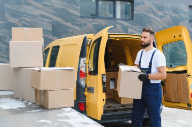 Bir şehir caddesinde karton bir kargo kamyonundan paket taşırken kurye teslimatı yapıyor.