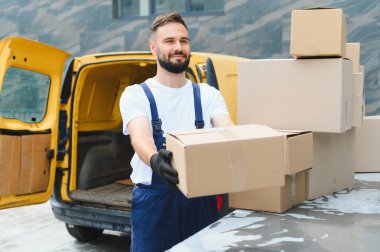 Kurye, açık dağıtım kamyonetinin yanındaki karton kutuda eldiven taşıyor. Nakliye ve lojistik konsepti.