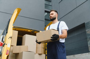 Kurye, açık bir teslimat minibüsünden kutuları indirirken, lojistik ve kentsel dağıtım dolandırıcılığını gözler önüne seriyor