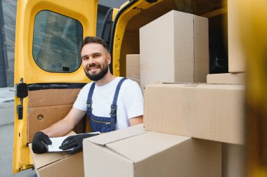 Bir kargo aracındaki paketleri kontrol ederken bir panoya kurye notları yazarak, müşteriler için verimli ve güvenilir hizmet sağlama