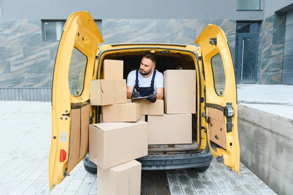 Karton kutularla dolu bir kargo aracının içindeki paketleri kontrol ederken panoya kurye yazma