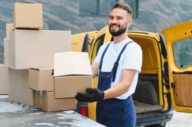 Eldiven takan teslimatçı, elinde bir karton kutuyla servis aracının yanında gülümseyen, verimli hizmet sunmaya hazır.