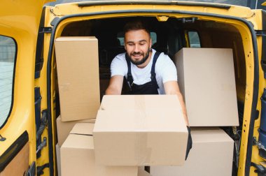 Paketler, nakliyat ve lojistik konseptiyle dolu ticari bir araçtan paket çıkaran kurye.