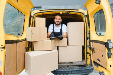 Paketlerle dolu bir kargo aracında çalışırken, kargo ve lojistiği yönetirken, panoya kurye yazması