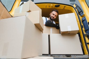 Bir dağıtım aracının arkasındaki paketleri kontrol ederken, lojistik ve nakliye işlerini yönetirken, karton panoya kurye yazma