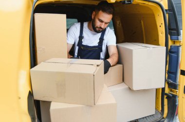 Karton kutuların nakliyesi ve taşınması için kargo aracında paketleri kontrol eden kurye