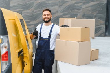 Karton kutuları, başarılı ve güvenilir nakliye hizmetlerini temsil eden bir kargo aracının yanında tutan kurye.