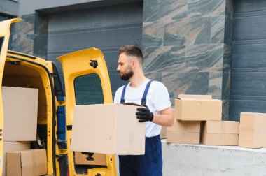 Parlak sarı bir teslimat minibüsünden paketleri getiren kurye yerleşim yerlerindeki müşterilere etkili bir şekilde paket taşıyor.