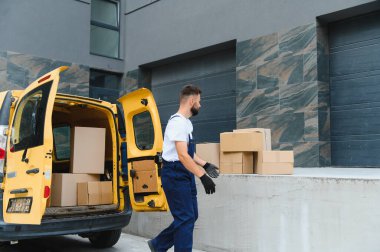 Bir teslimat minibüsünden paketler taşıyan kurye, modern ticareti yöneten temel nakliye ve lojistik hizmetlerini temsil ediyor.