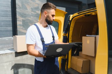 Eldiven takan ve bir teslimat servisi için çalışırken karton kutuları kontrol eden bir kurye.