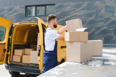 Ticari bir araçtan paketler taşıyan kurye karton kutuları nakliye ve teslimat için yönetiyor.