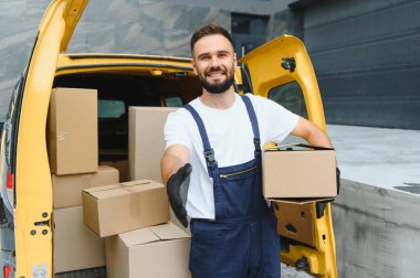Karton kutuyu tutarken el sıkışmak için kurye uzatıyor, paketler dolu açık teslimat kamyonunun yanında duruyor, başarılı ve güvenilir nakliye servisini simgeliyor.
