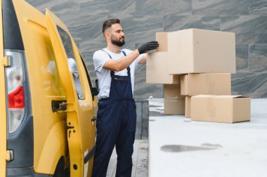 Eldiven giyen kurye teslimat için paketleri düzenliyor, lojistik ve ulaşımı verimlilik ve özenle yönetiyor.