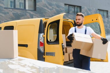 Ticari bir araçtan paketler taşıyan kurye verimli ve güvenilir nakliye hizmetleri sunuyor.