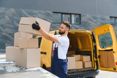 Eldivenleri dikkatlice paketleyip ticari bir minibüsün tepesindeki kutuya koyan kurye teslimata hazırlanıyor.