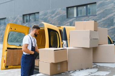 Kargo için kurye paketleri hazırlıyor, karton kutuları parlak sarı bir teslimat aracına yüklüyor, verimli ulaşım ve lojistik