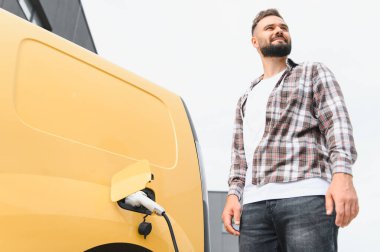 Dağıtım şöförü şarj istasyonunda elektrikli minibüs, çevre dostu ulaşım ve sürdürülebilir lojistik