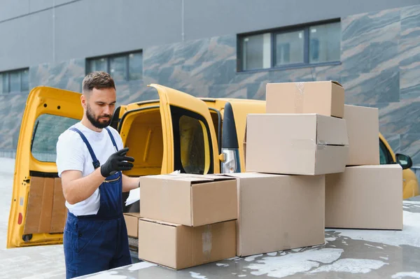 Eldiven giyen kurye, karton kutuları kontrol ediyor ve düzenliyor. Sarı teslimat minibüsünün üstünde, verimli paket nakli ve lojistik...
