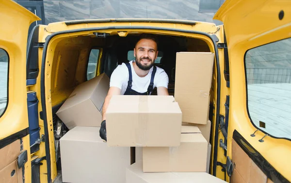 Paketlerle dolu sarı bir minibüsten paket taşıyan kurye, ekspres nakliye ve lojistik hizmetleri sağlıyor.