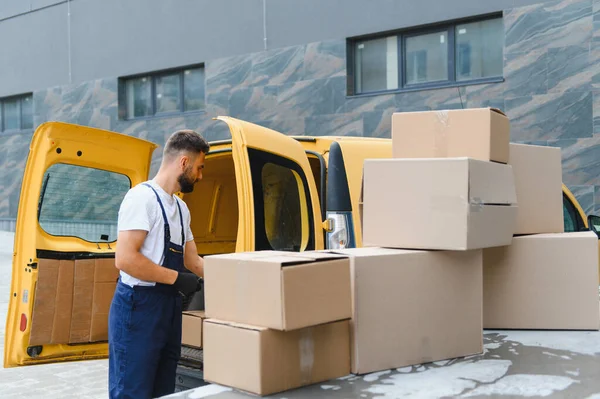 Kargo için kurye paketleri hazırlıyor, karton kutuları parlak sarı bir teslimat aracına yüklüyor, verimli ulaşım ve lojistik
