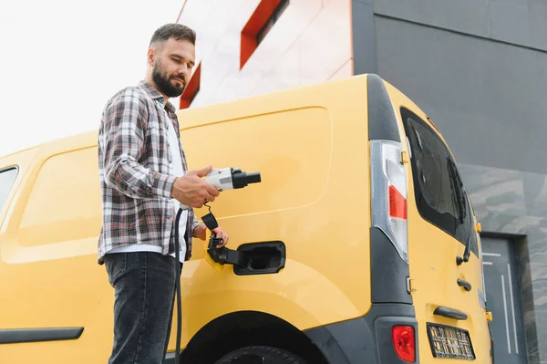 Dağıtım şöförü kabloyu tutuyor, elektrik dağıtım kamyonunu şarj etmeye hazırlanıyor, sürdürülebilir ulaşımı teşvik ediyor.