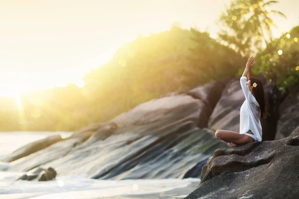 Frauen-Yoga meditiert auf einem Felsen am Strand des Ozeans — Stockfoto