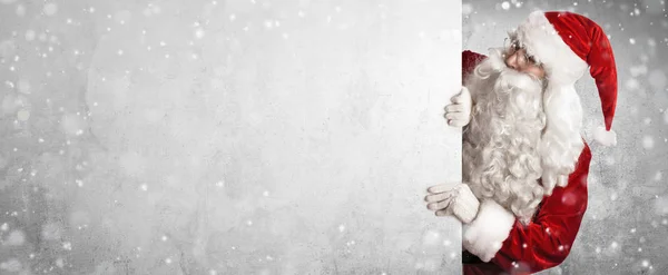 Weihnachtsmann zeigt etwas an einer weißen Wand — Stockfoto