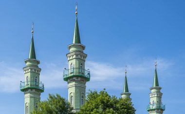 Mavi yaz gökyüzünün arka planında bir Müslüman camisinin dört yeşil minaresi
