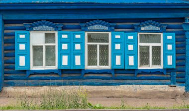 Doku, eski ahşap bir ahşap evin duvarı, açık pencere panjurları, mavi boyanmış.