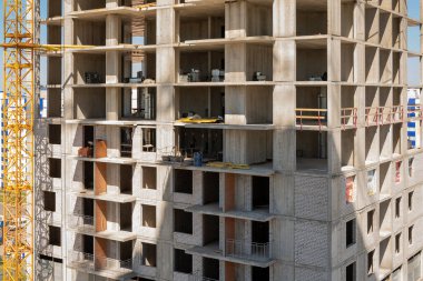 İnşaat halindeki çok katlı bir binanın açık ve kapalı iskan bölümleri ve vinç parçaları olan bir parçası.