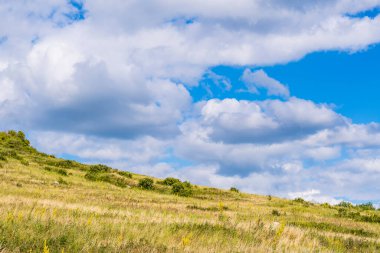 Toratau 'lu Shihan' ın eteğindeki tepedeki yeşil çayır mavi bulutlu yaz gökyüzüne karşı. Sterlitamak ve Ishimbay 'in banliyöleri.