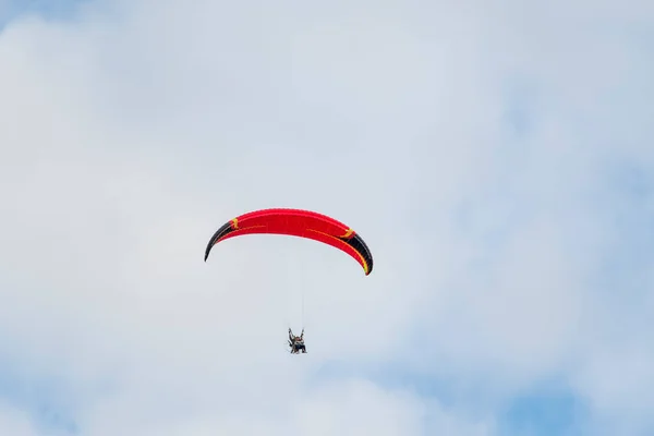 一群人站在一辆电动滑翔机的红色圆顶下 在蓝天的映衬下在空中飞舞 红色圆顶的机动滑翔机在蓝色的夏夜天空下 — 图库照片