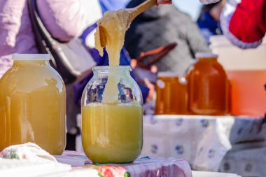 Bir adam kavanoza bal koymak için tahta kaşık kullanıyor..