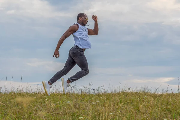 Genç ve güçlü bir atlet, mavi bir yaz gökyüzüne değmeden yeşil bir alana atlıyor..