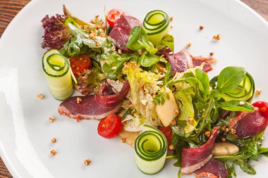 Salad with duck and vegetables on white plate