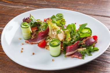 Salad with duck and vegetables on white plate