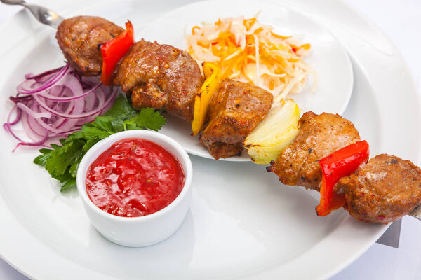 shashlik on skewer with red sauce on white plate