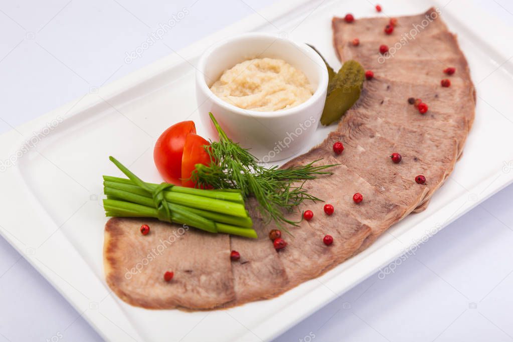 Beef tongue with horseradish on white plate