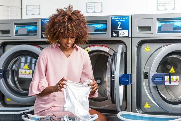 Jonge zwarte Afrikaanse Amerikaanse vrouw haar kleren wassen in een auto — Stockfoto