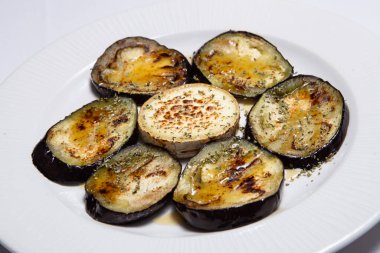 Beyaz bir tabakta kömürde pişirilmiş bir ızgara patlıcan