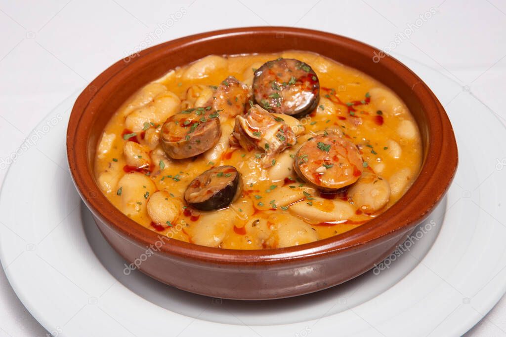 Beans and bacon stew served in a casserole dish. Spanish cuisine. Selective focus. Judiones de la Granja