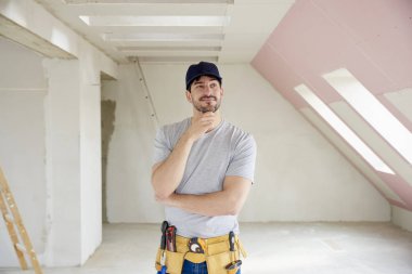 Onun çene ayakta inşaat sahasında üzerinde el ile düşünme genç tamirci portresi.