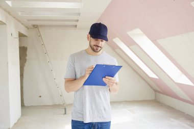 Pano inşaatı yerinde dururken elinde tutan genç tadilat işçisi. 