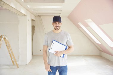 Pano inşaatı yerinde dururken elinde tutan genç tadilat işçisi. 