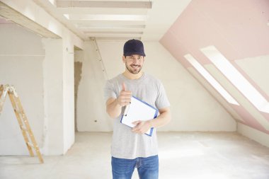 Pano elinde tutan ve inşaatı yerinde dururken Yaşasın vererek genç tadilat işçisi. 