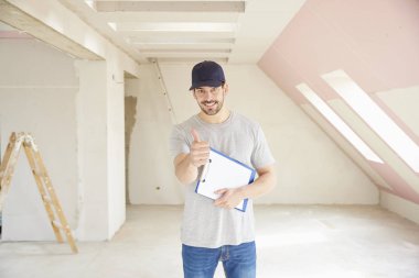 Pano elinde tutan ve inşaatı yerinde dururken Yaşasın vererek genç tadilat işçisi. 