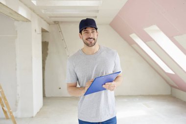 Pano inşaatı yerinde dururken elinde tutan genç tadilat işçisi. 